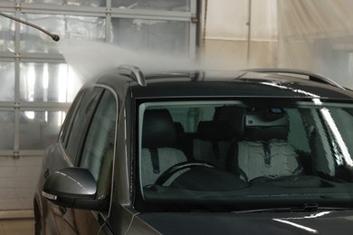 Washing auto with high pressure water jet at car wash, closeup