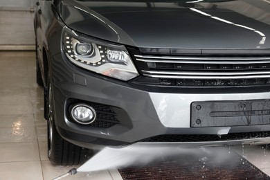 Photo of Washing auto with high pressure water jet at car wash, closeup