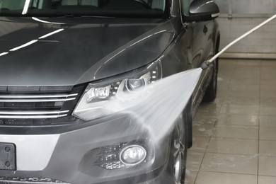 Washing auto with high pressure water jet at car wash, closeup