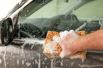 Photo of Man washing auto with sponge at car wash, closeup