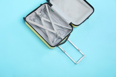 Open empty suitcase on light blue background, top view