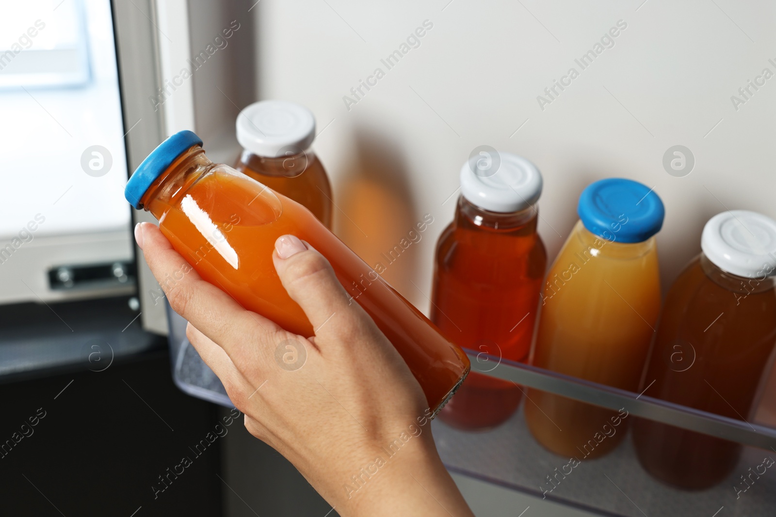 Photo of Woman taking bottle of juice from refrigerator, closeup