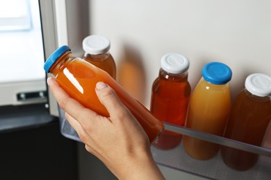 Photo of Woman taking bottle of juice from refrigerator, closeup