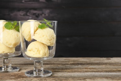 Photo of Scoops of melon sorbet and mint in glass dessert bowls on wooden table, space for text