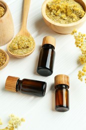 Photo of Tinctures in bottles and helichrysum flowers on white wooden table