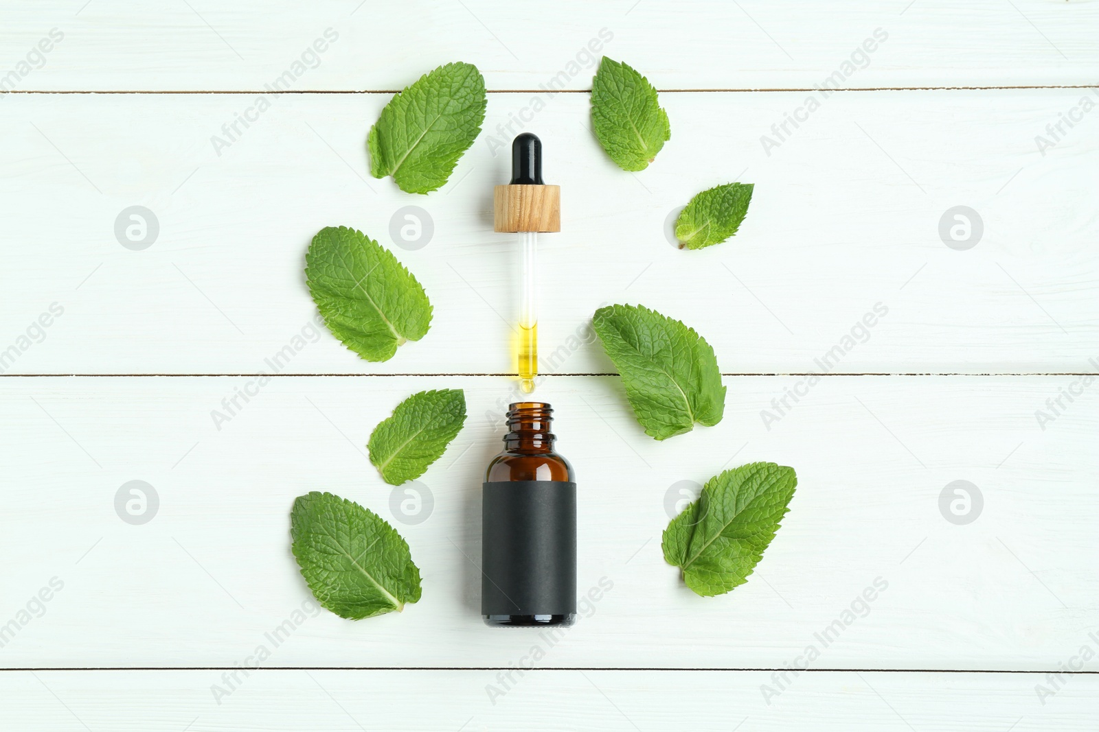 Photo of Dripping tincture from pipette into bottle and mint on white wooden table, flat lay