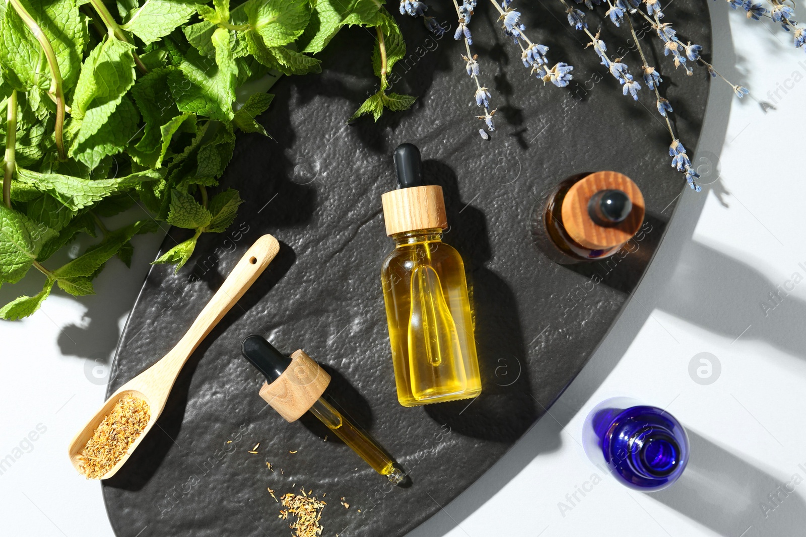 Photo of Tinctures in bottles and medicinal herbs on white table, top view