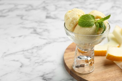 Photo of Scoops of melon sorbet with mint in glass dessert bowl on light marble table, space for text