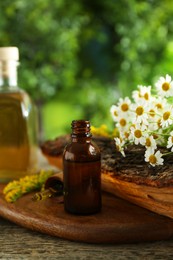 Photo of Tincture in bottle, pipette, goldenrods and chamomile flowers on wooden table