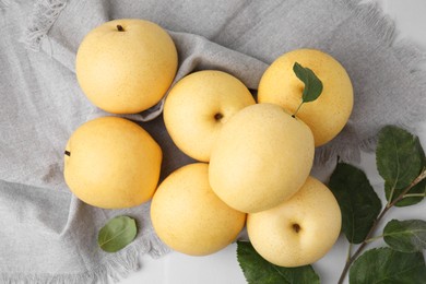 Photo of Delicious fresh apple pears and green leaves on white table, top view