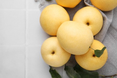 Photo of Delicious fresh apple pears and green leaves on white table, top view. Space for text