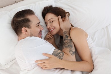 Photo of Happy couple lying on bed at home