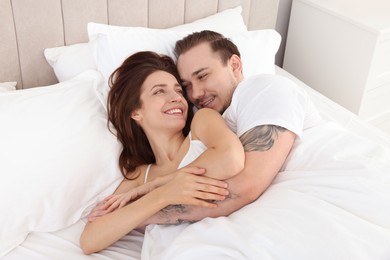 Happy couple hugging in bed at home