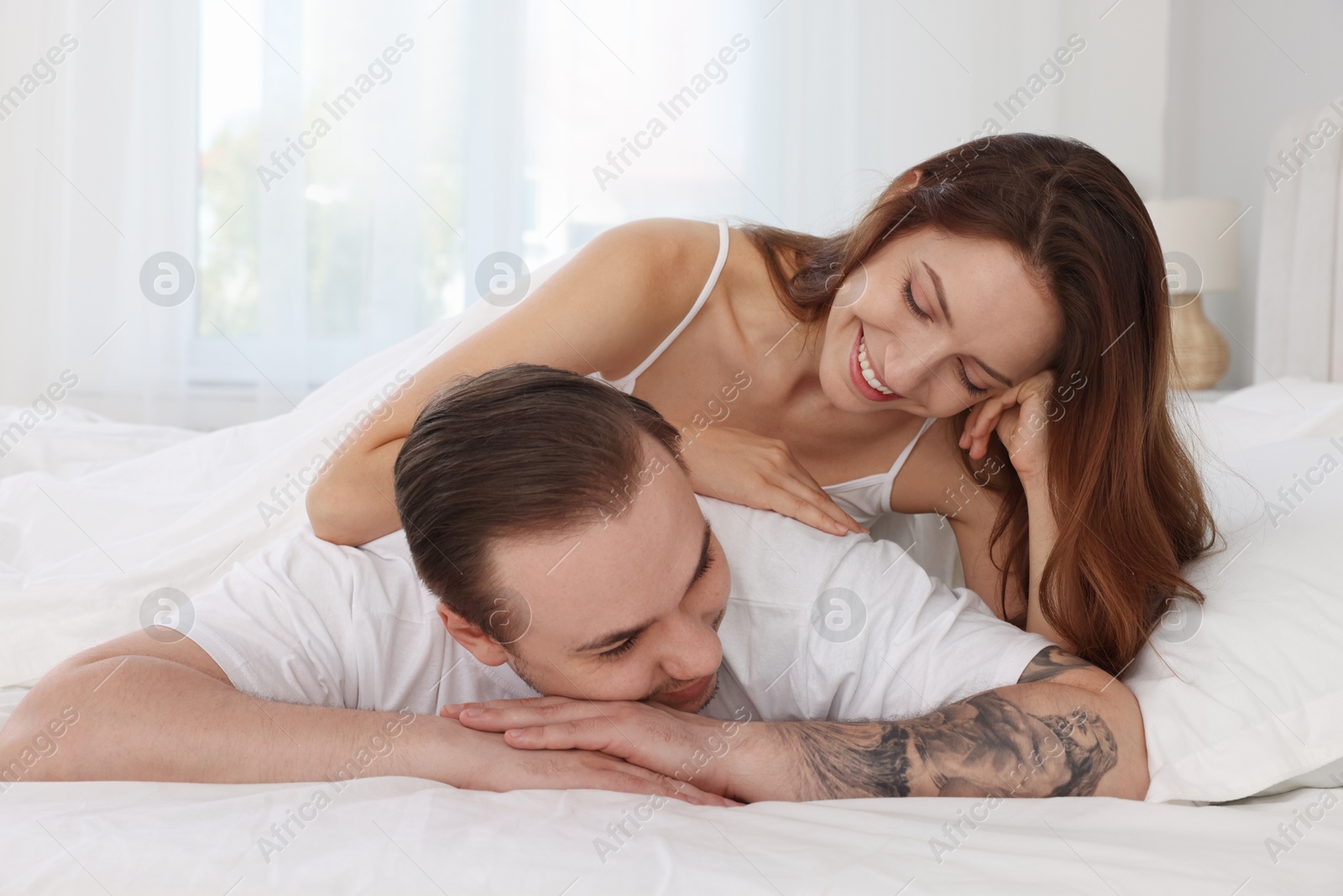 Photo of Happy couple spending time together on bed at home