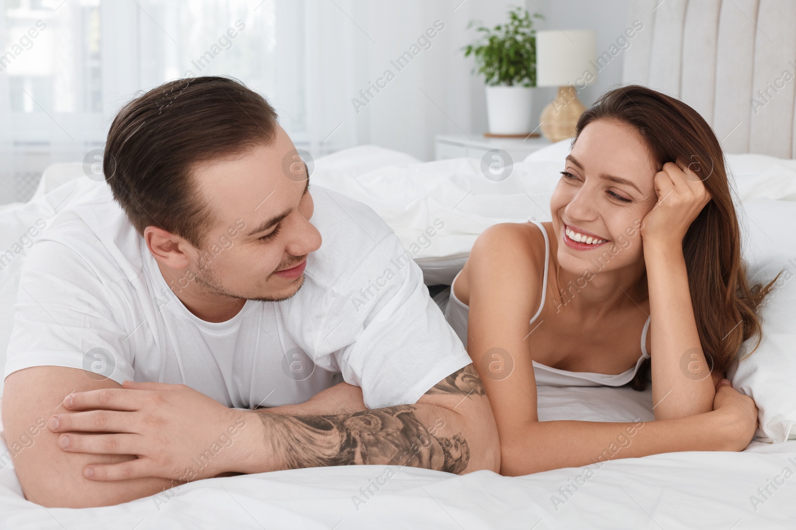 Photo of Happy couple spending time together on bed at home