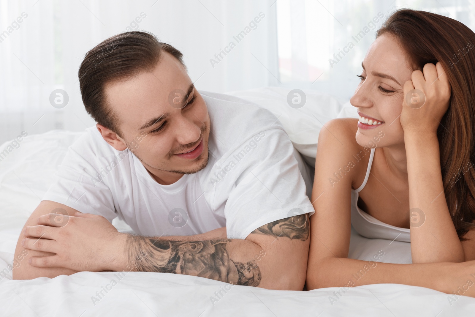 Photo of Happy couple spending time together on bed at home