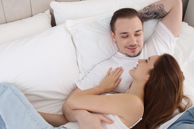 Photo of Happy couple spending time together on bed at home