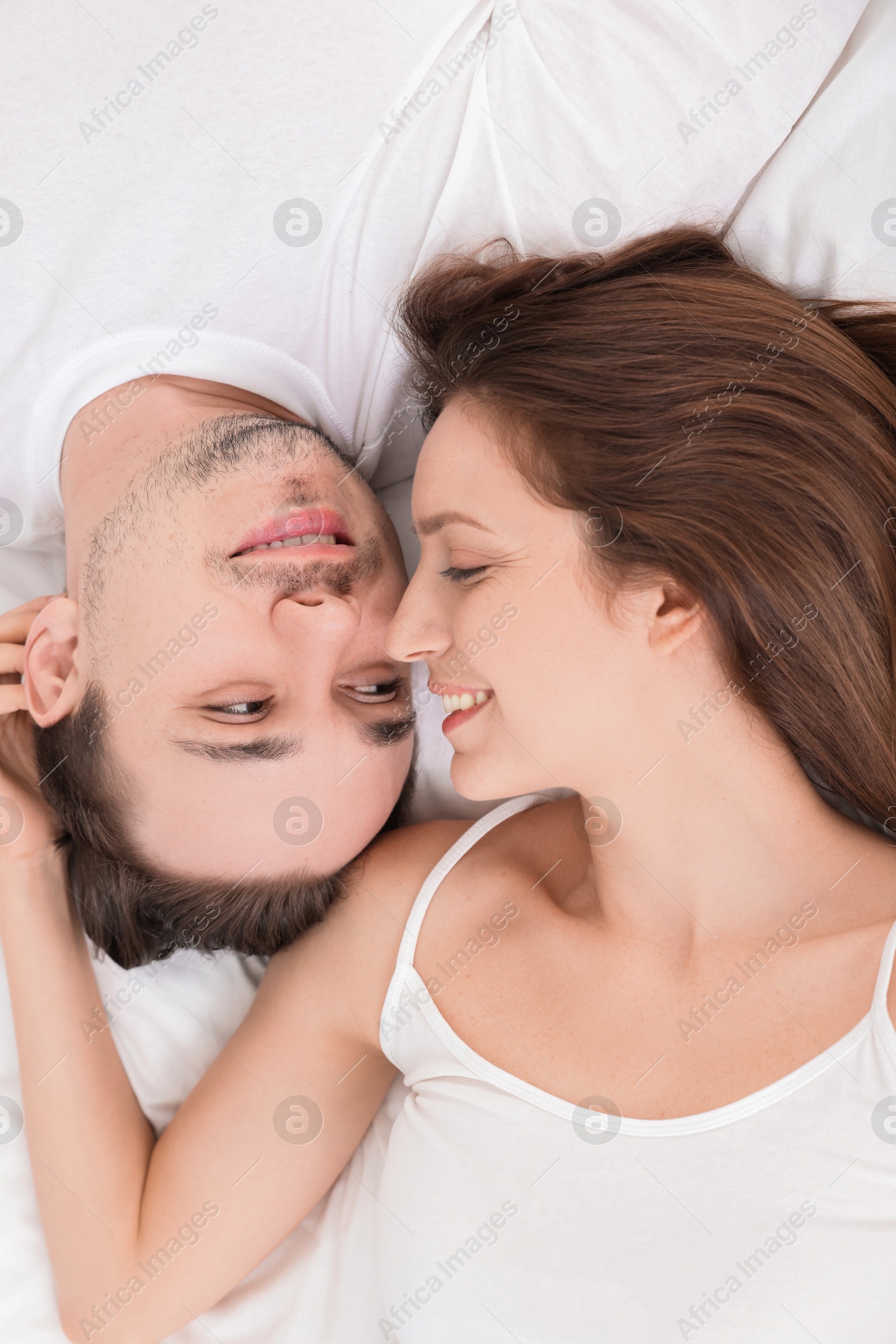 Photo of Happy couple spending time together on bed at home, top view