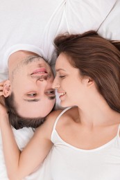 Happy couple spending time together on bed at home, top view