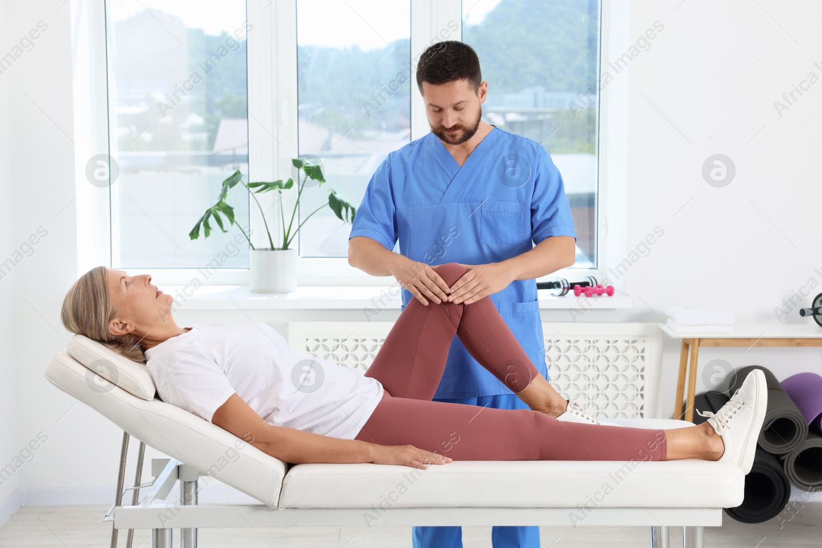 Photo of Physiotherapist working with senior patient in rehabilitation center