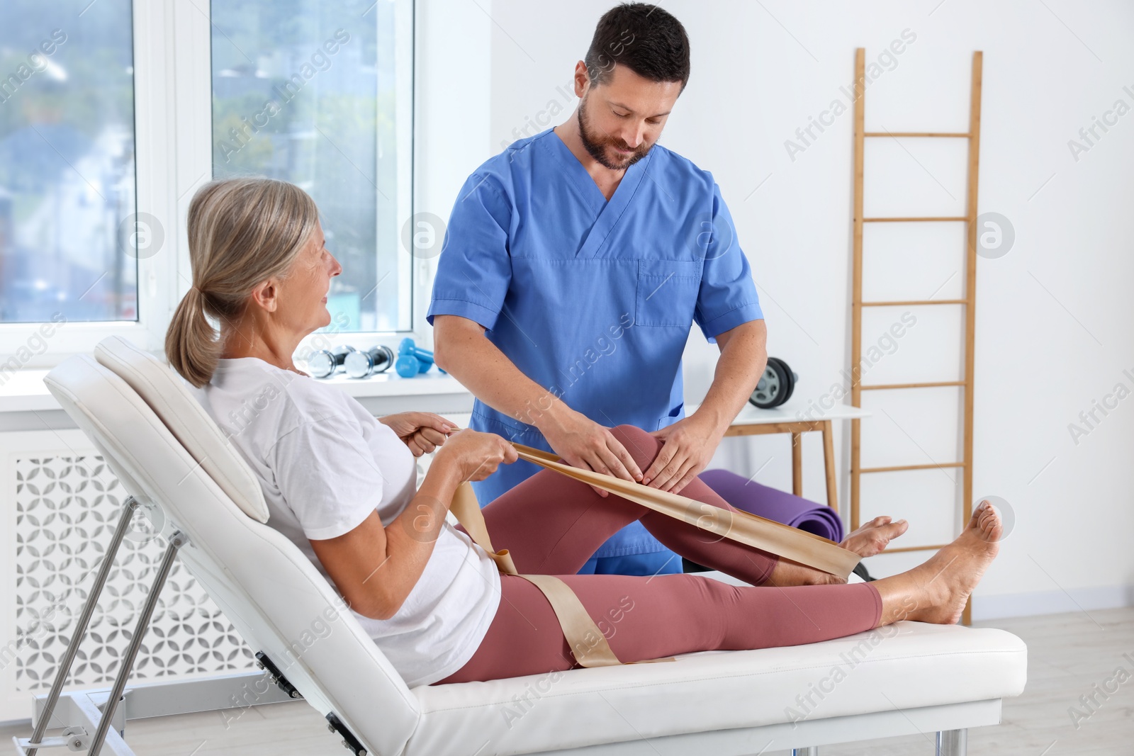 Photo of Physiotherapist working with senior patient in rehabilitation center