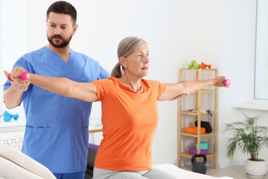 Photo of Senior patient exercising under physiotherapist supervision in rehabilitation center