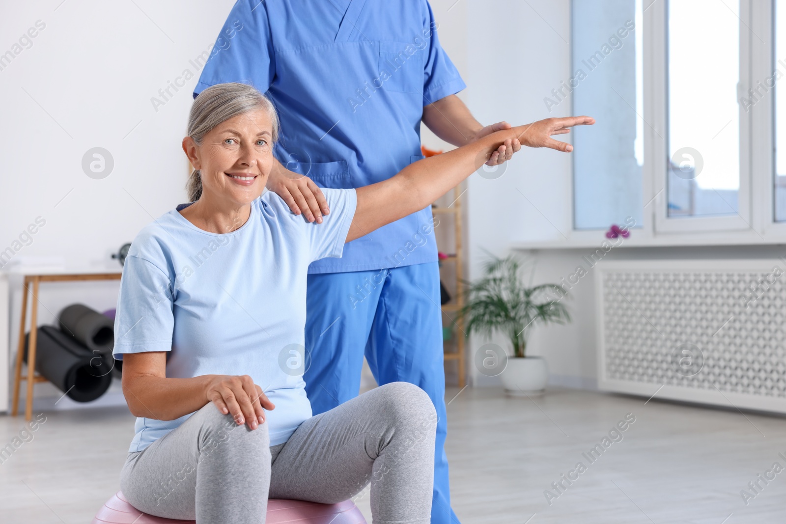 Photo of Physiotherapist working with senior patient in rehabilitation center