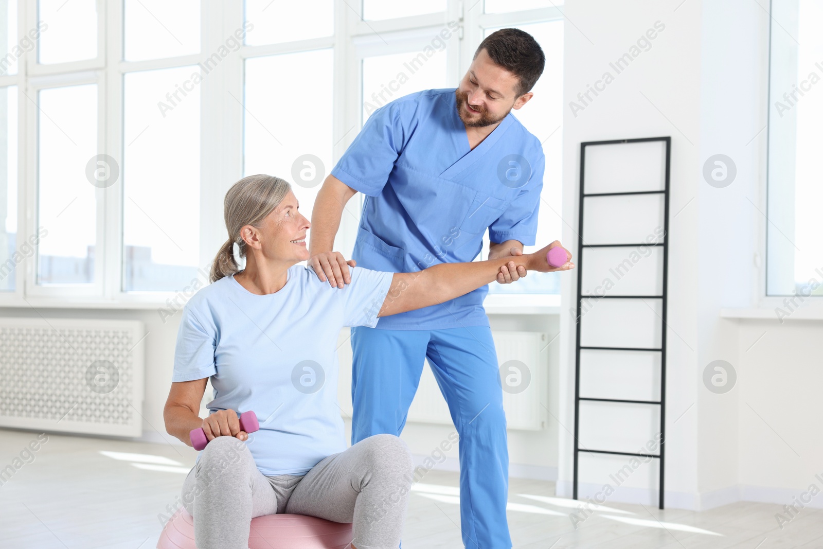 Photo of Senior patient exercising under physiotherapist supervision in rehabilitation center