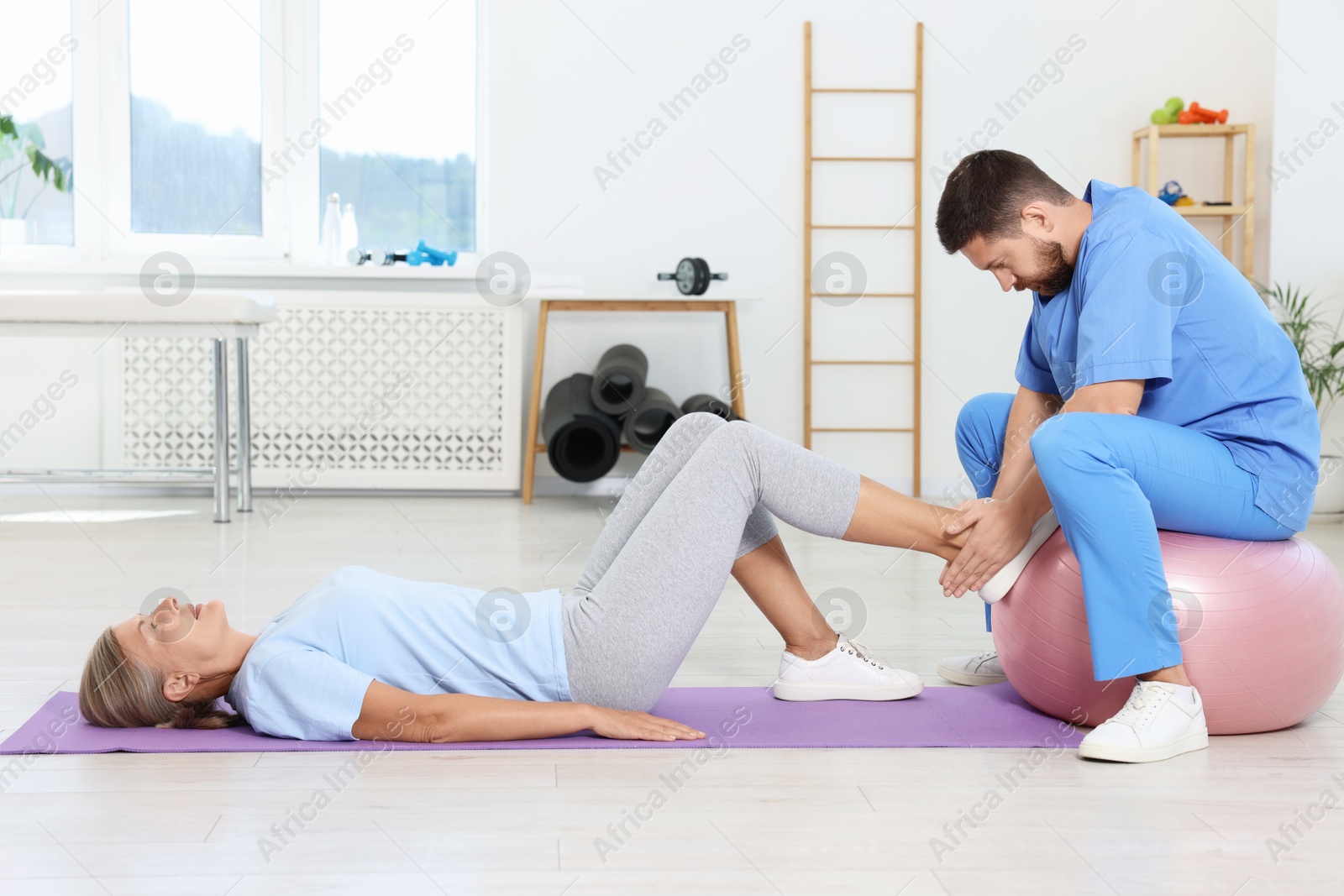 Photo of Physiotherapist working with senior patient in rehabilitation center