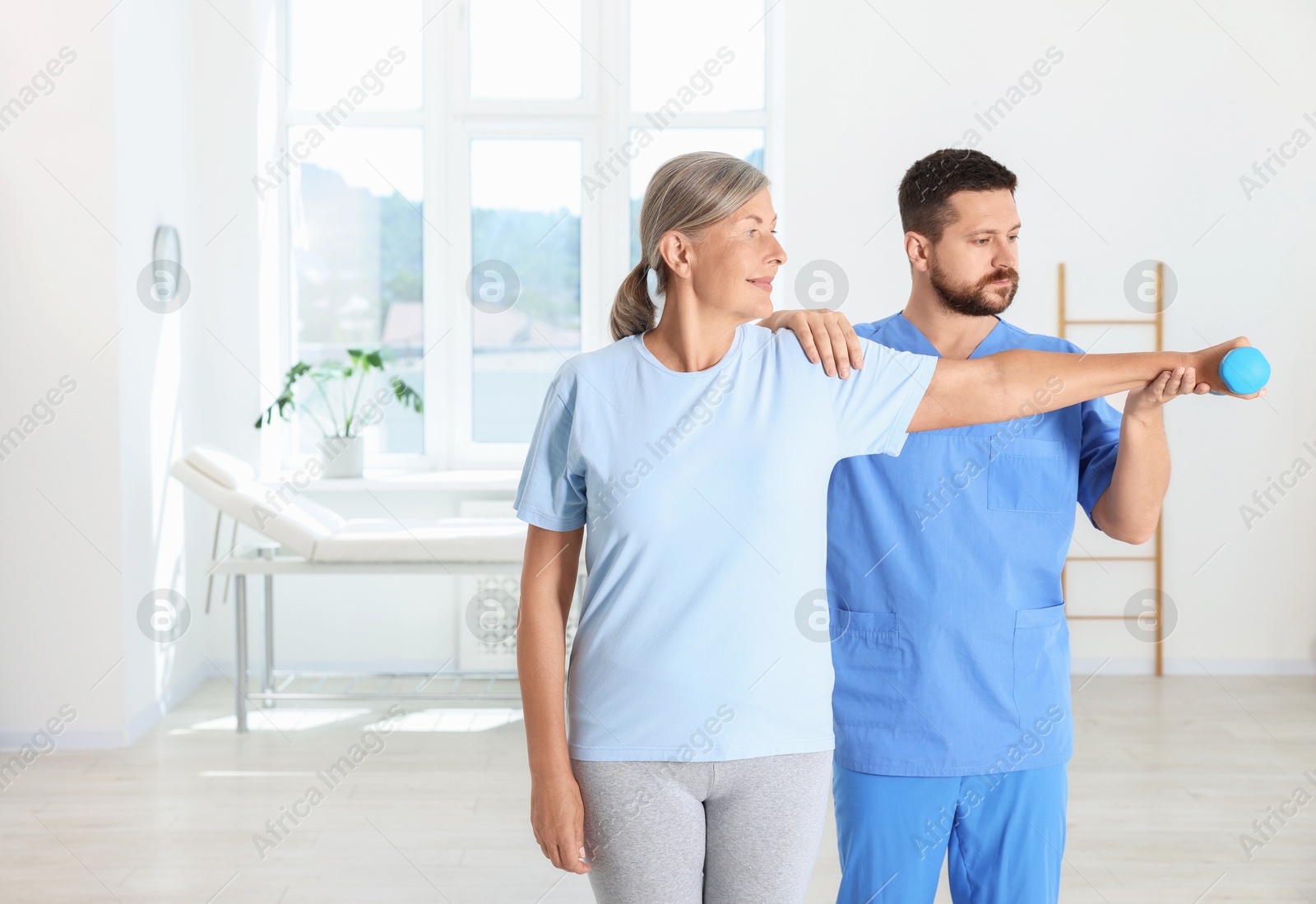 Photo of Senior patient exercising under physiotherapist supervision in rehabilitation center