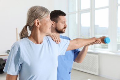 Photo of Senior patient exercising under physiotherapist supervision in rehabilitation center