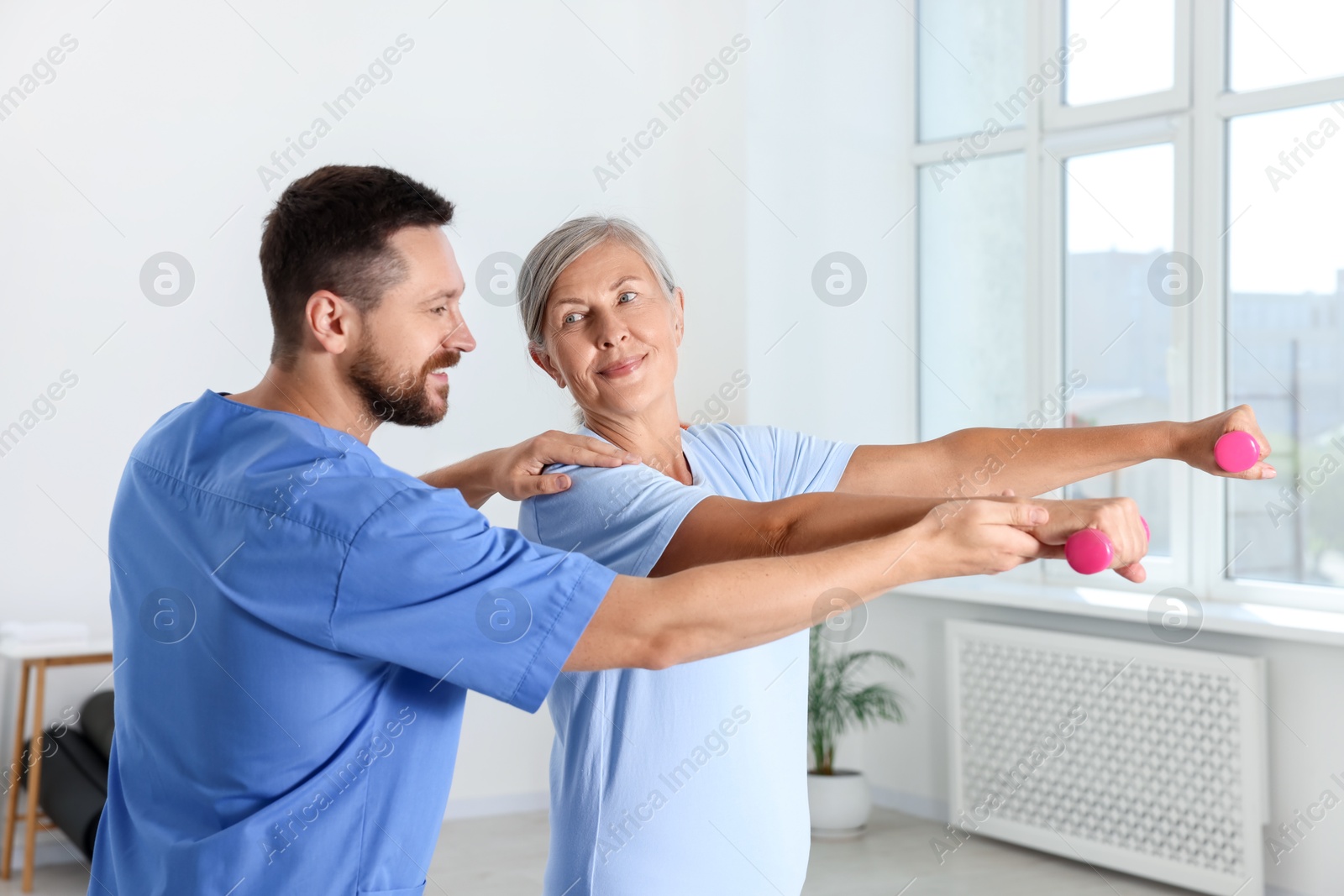 Photo of Senior patient exercising under physiotherapist supervision in rehabilitation center