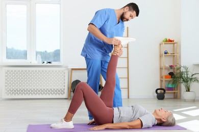 Photo of Physiotherapist working with senior patient in rehabilitation center