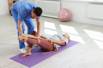 Photo of Physiotherapist working with senior patient in rehabilitation center