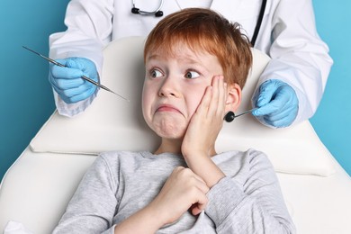 Photo of Dental phobia. Dentist working with scared little boy on light blue background