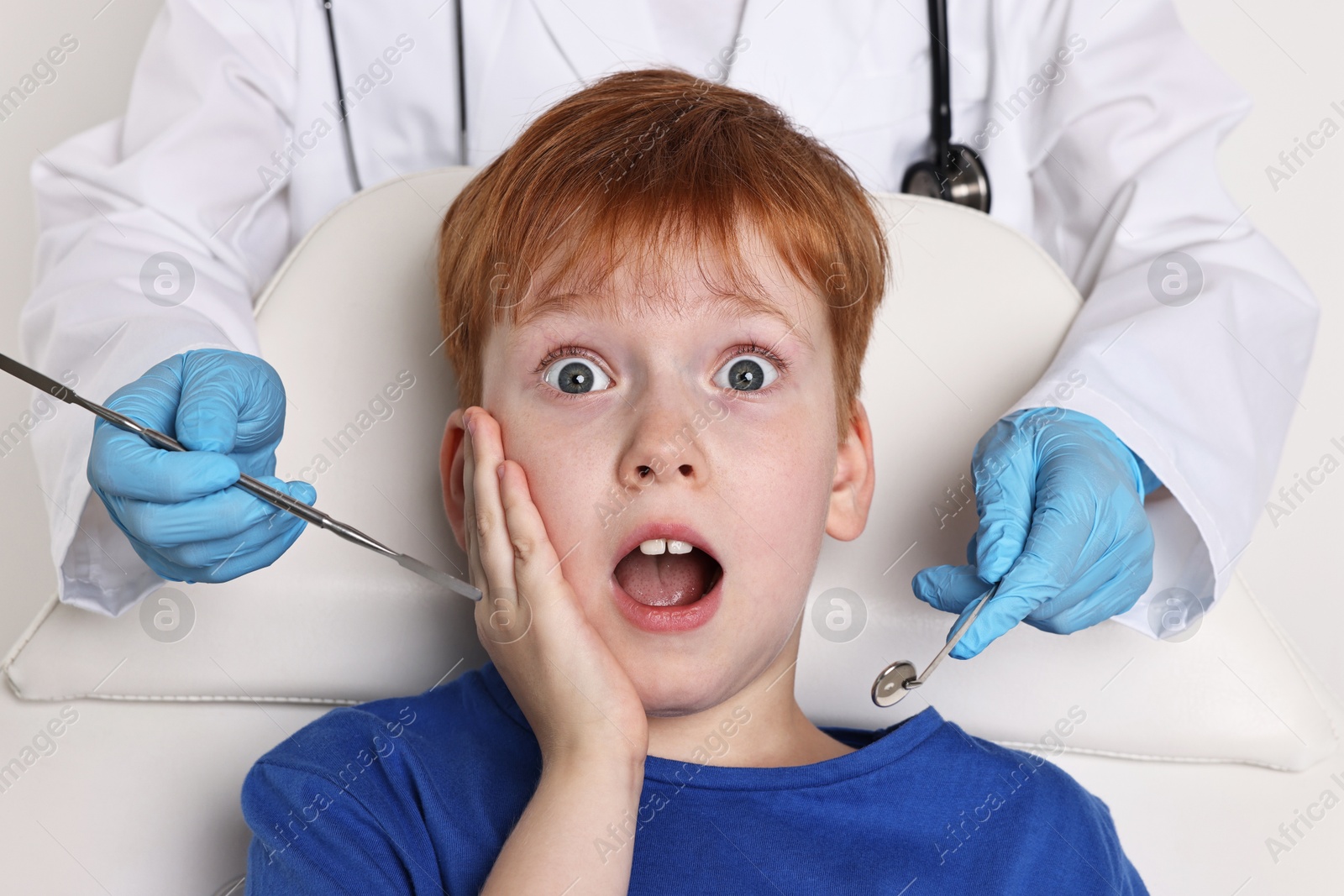 Photo of Dental phobia. Dentist working with scared little boy