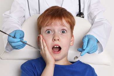 Photo of Dental phobia. Dentist working with scared little boy