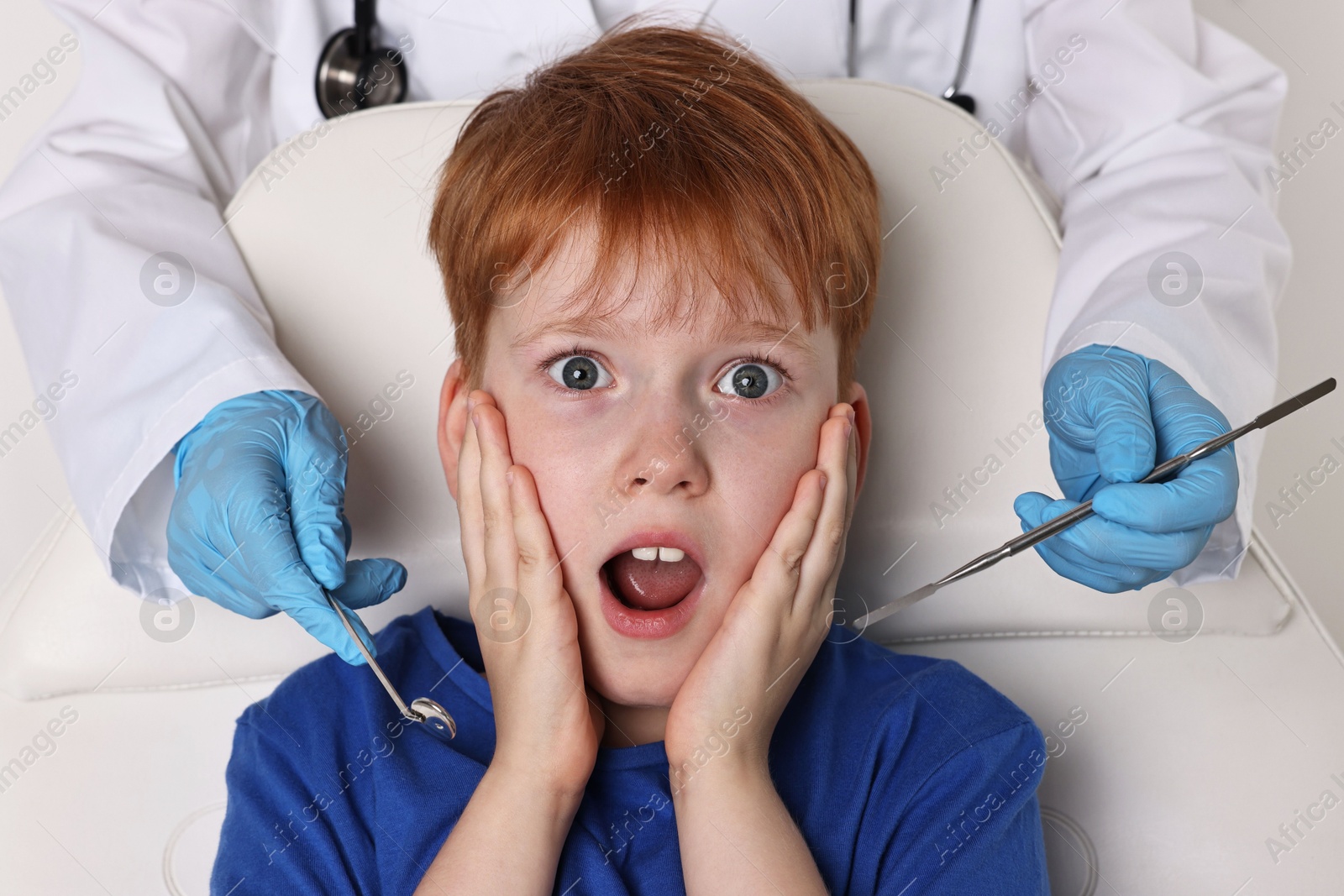 Photo of Dental phobia. Dentist working with scared little boy