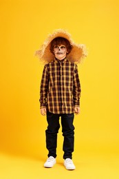 Photo of Funny boy dressed like scarecrow on yellow background. Halloween celebration