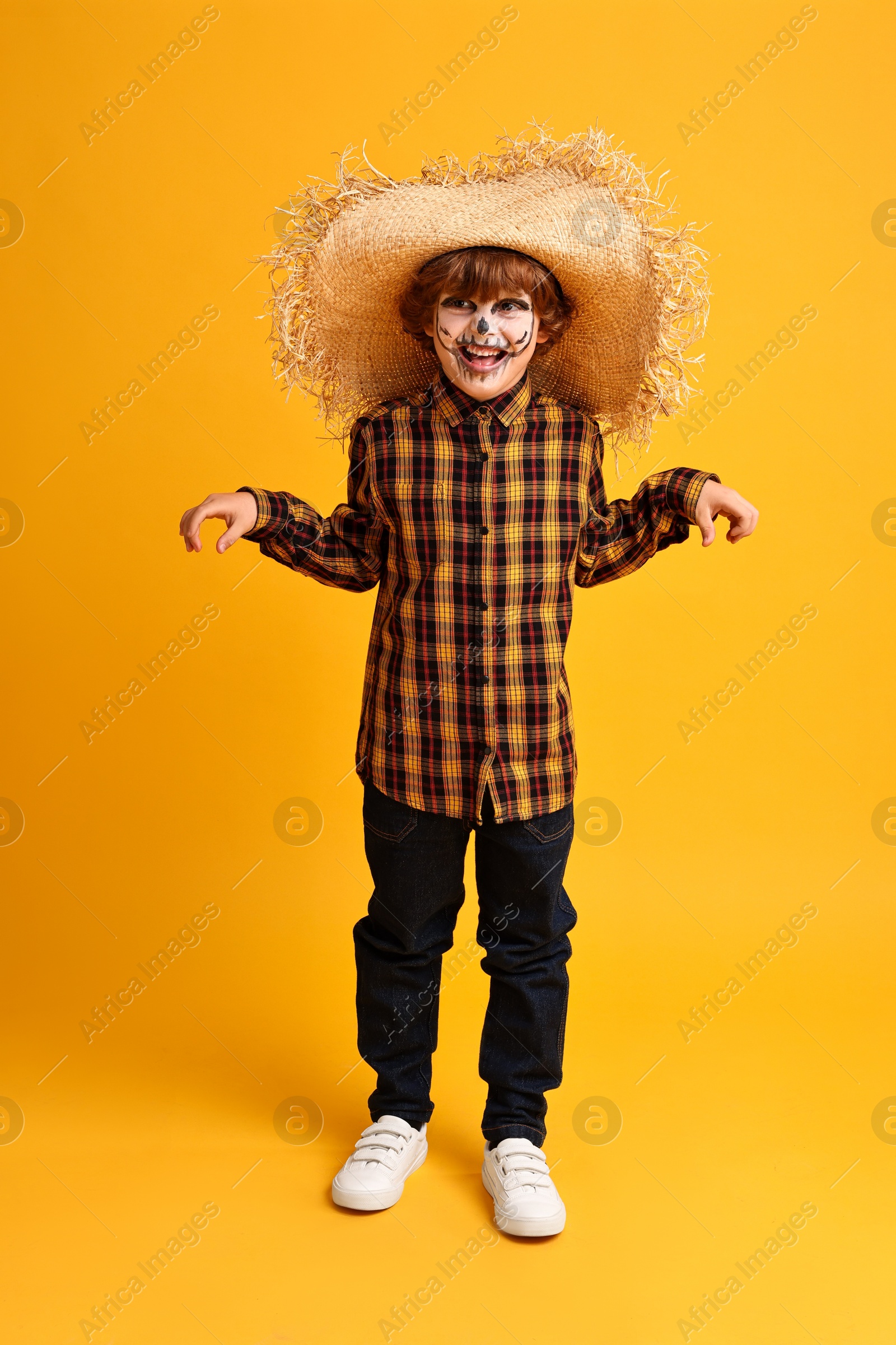 Photo of Funny boy dressed like scarecrow on yellow background. Halloween celebration