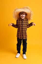 Photo of Funny boy dressed like scarecrow on yellow background. Halloween celebration