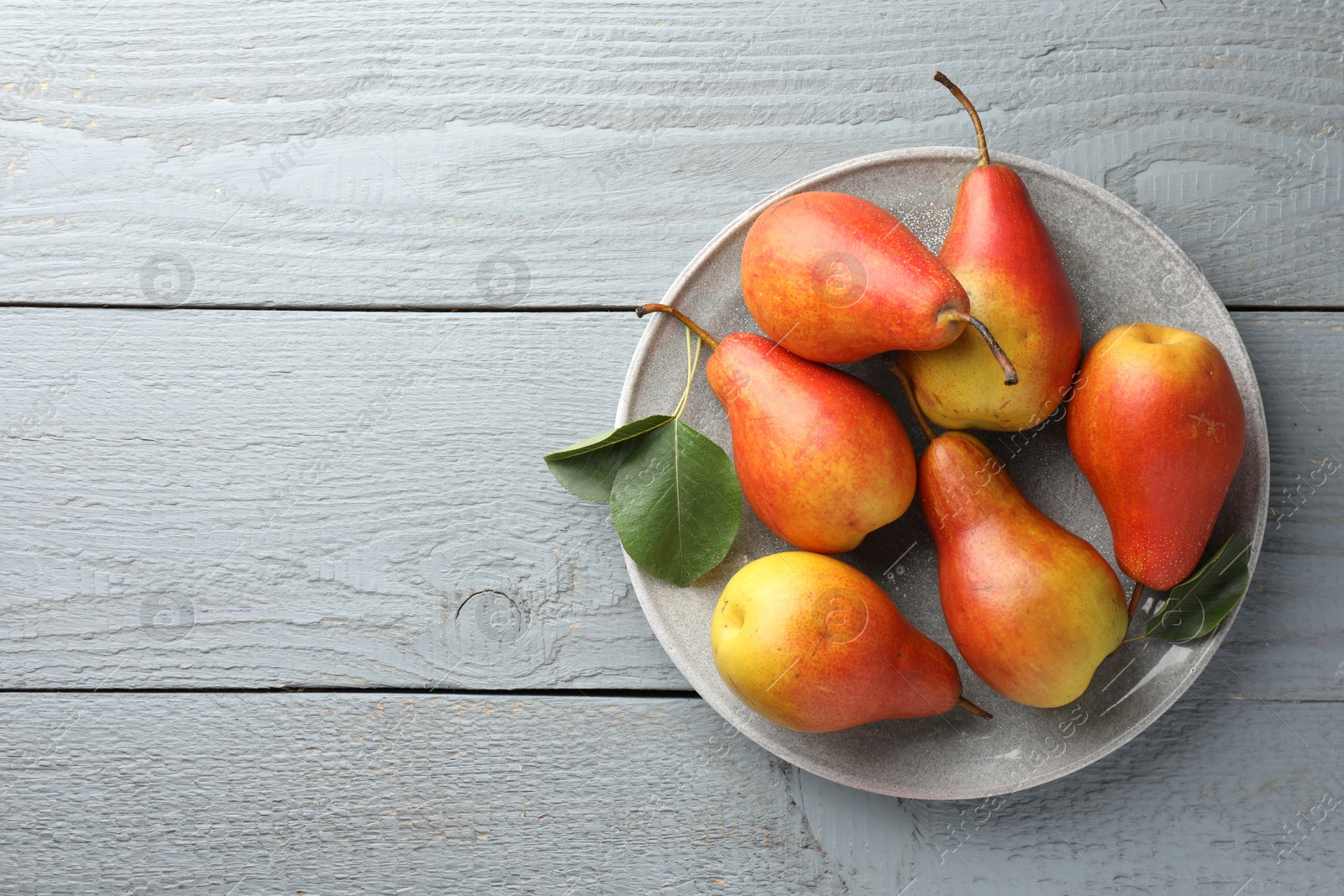 Photo of Ripe juicy pears on grey wooden table, top view. Space for text