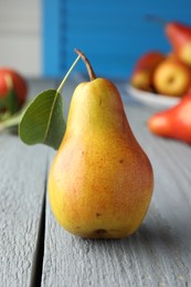 Photo of Ripe juicy pear with green leaf on grey wooden table