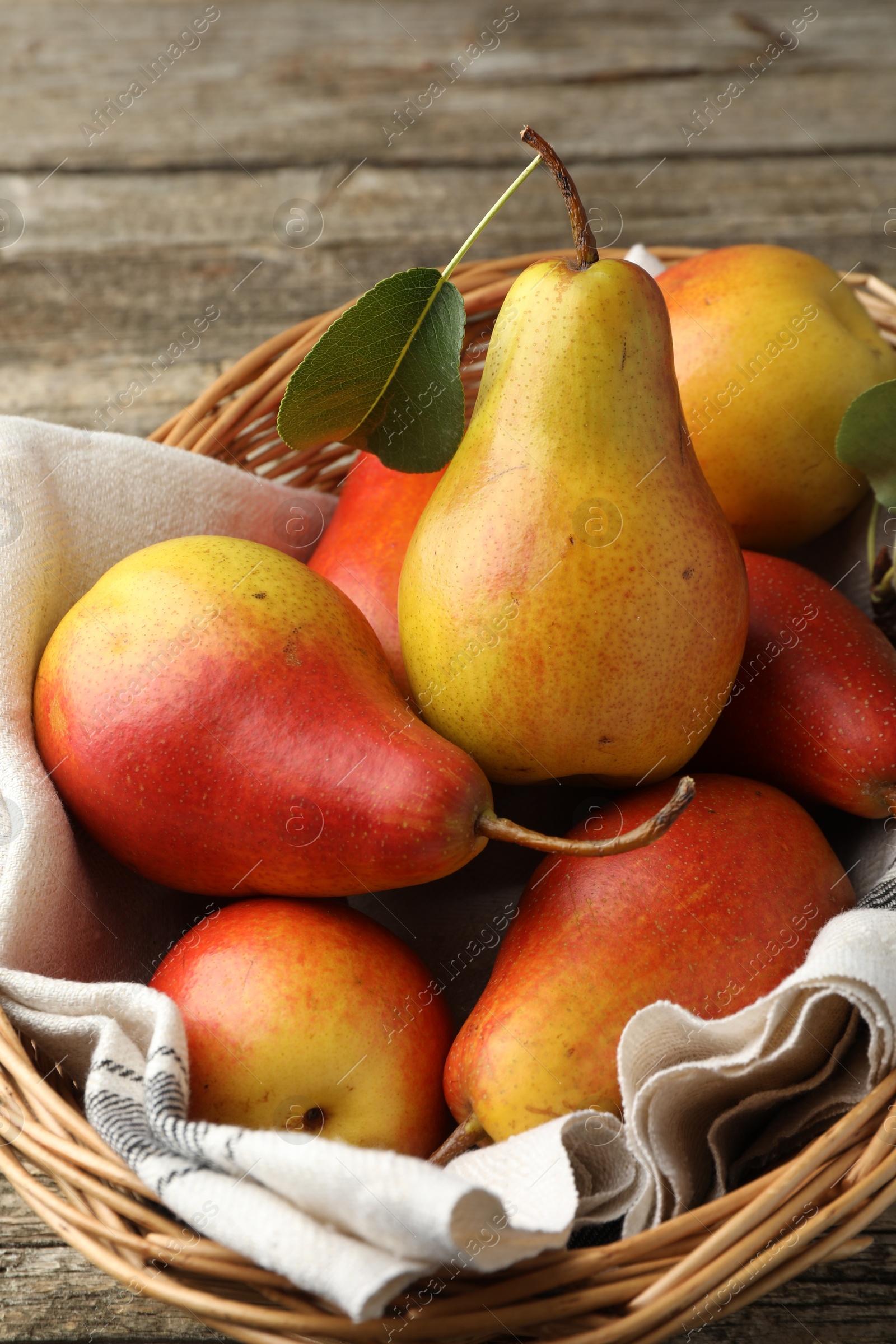 Photo of Ripe juicy pears in wicker basket on wooden table, closeup