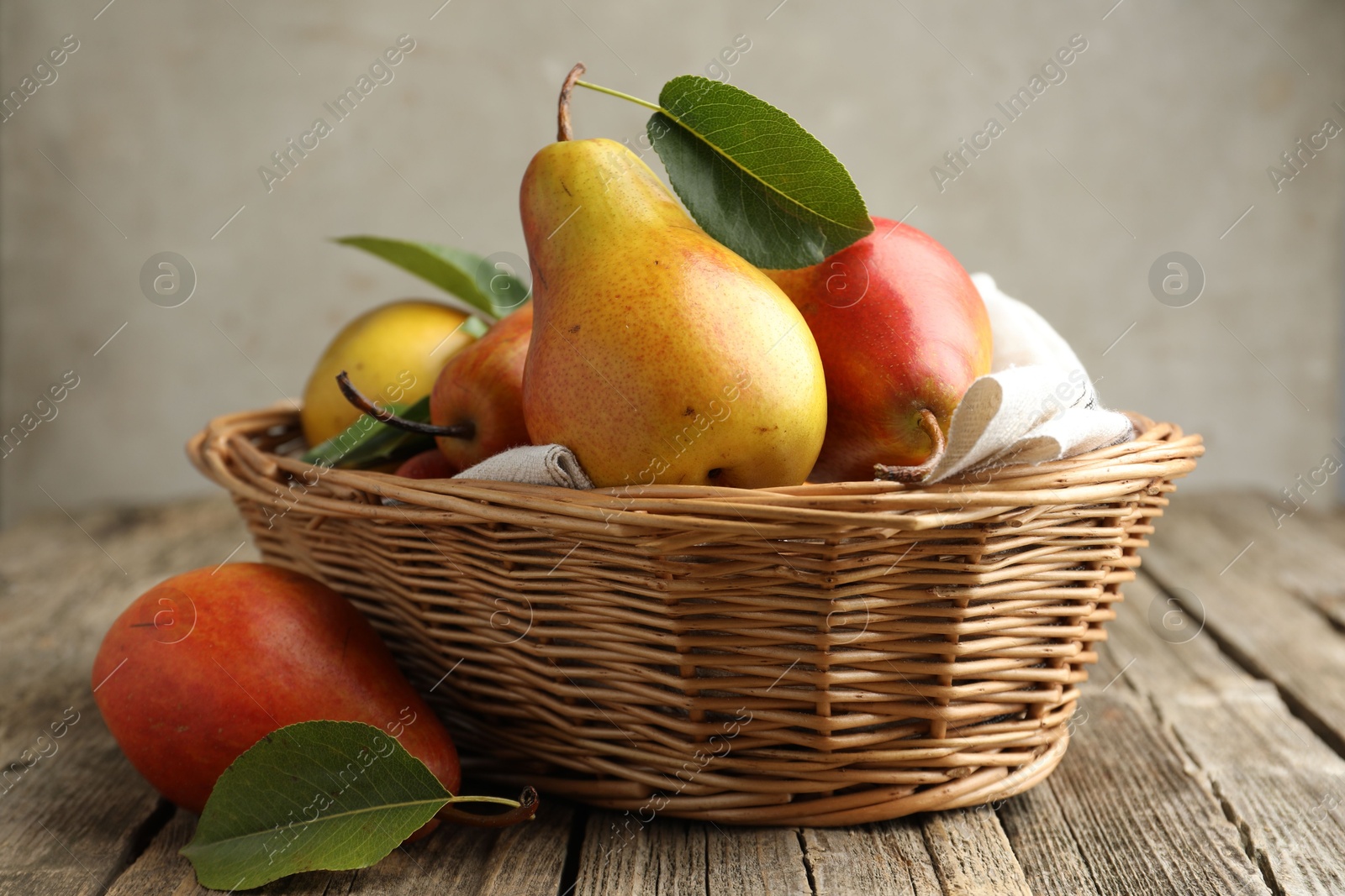 Photo of Ripe juicy pears in wicker basket on wooden table