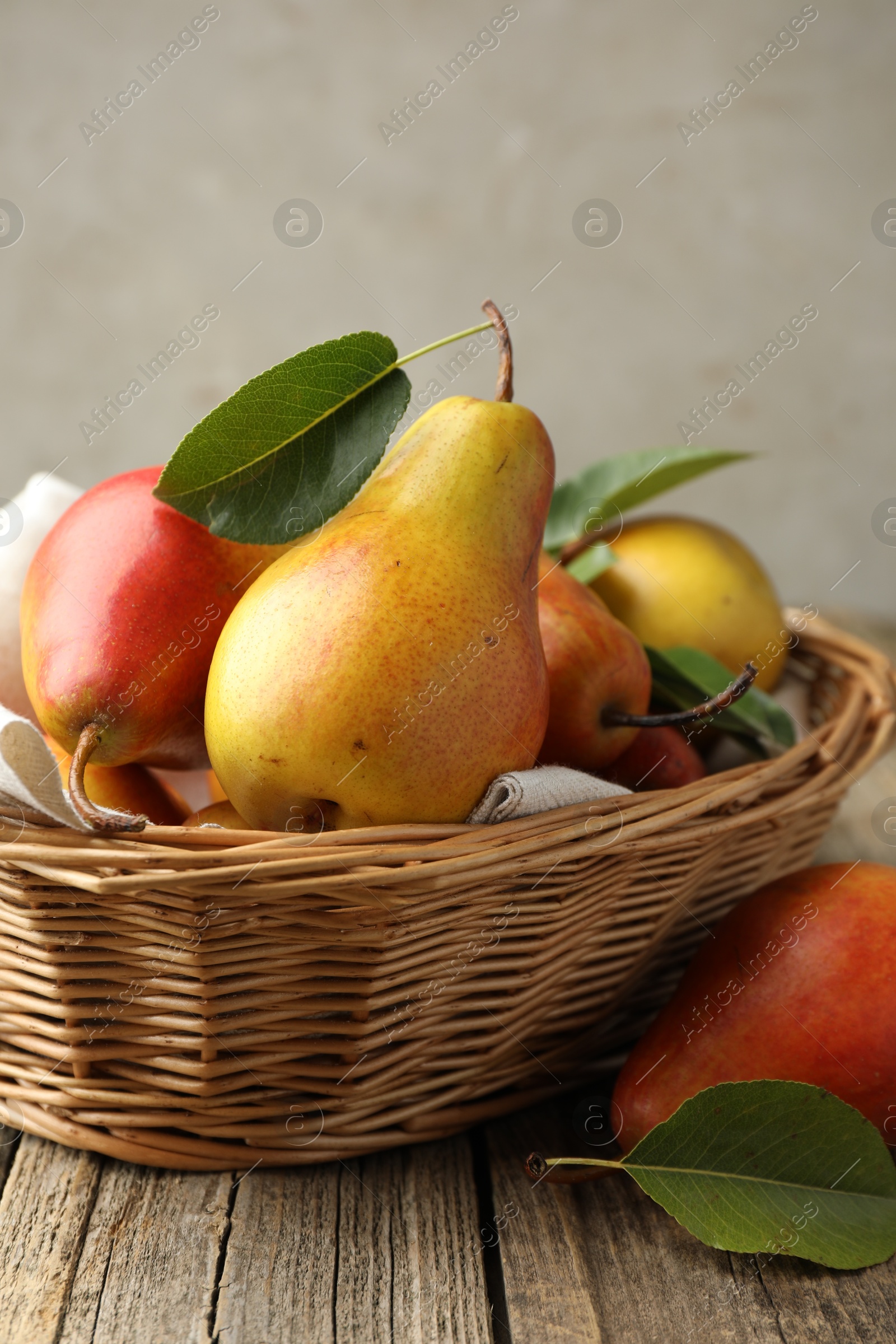 Photo of Ripe juicy pears in wicker basket on wooden table