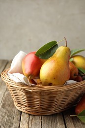 Photo of Ripe juicy pears in wicker basket on wooden table