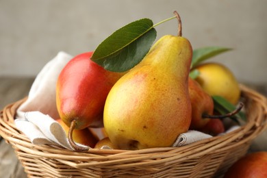 Photo of Ripe juicy pears in wicker basket on table, closeup