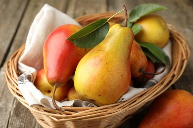 Photo of Ripe juicy pears in wicker basket on wooden table, closeup