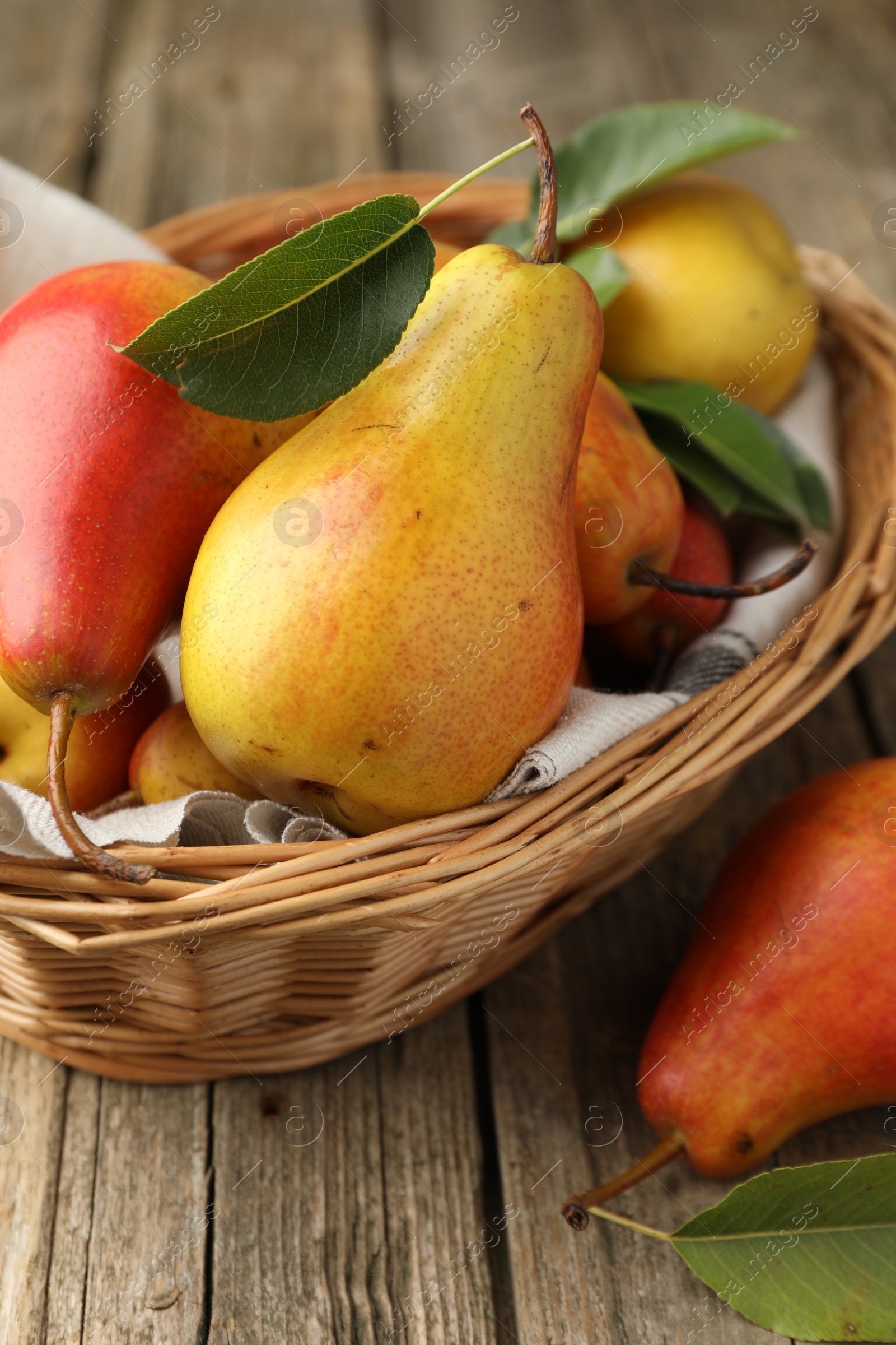 Photo of Ripe juicy pears in wicker basket on wooden table, closeup